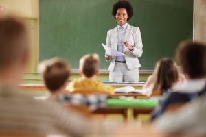Happy black teacher giving a lecture at elementary school.