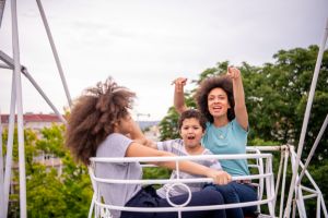 Cheerful Mother and Lovely Kids of African-American Ethnicity are Having Fun in Luna Park.