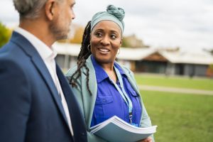Cheerful female teacher talking with male colleague outdoors