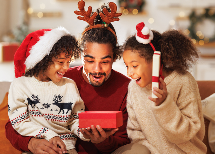 Happy afro american curly kids with dad opening christmas present, smiling at camera