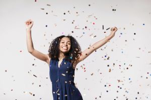 Joyful woman laughing, dancing and has fun with falling confetti. Enjoying life, celebration concepts
