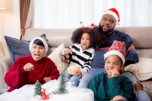 Happiness African family watching movie with excited and fun in the living room for leisure with comfort at home on Christmas day, dad and mom and daughter cheering watching tv with victory.