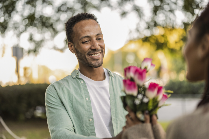 african american man giving flowers to his girlfriend for valentines day, anniversary, just married, honeymoon,