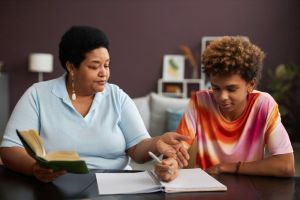 Confident mature female tutor explaining something to teenage boy