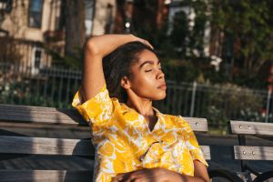 Woman relaxing on a bench enjoying a wam sun at sunset
