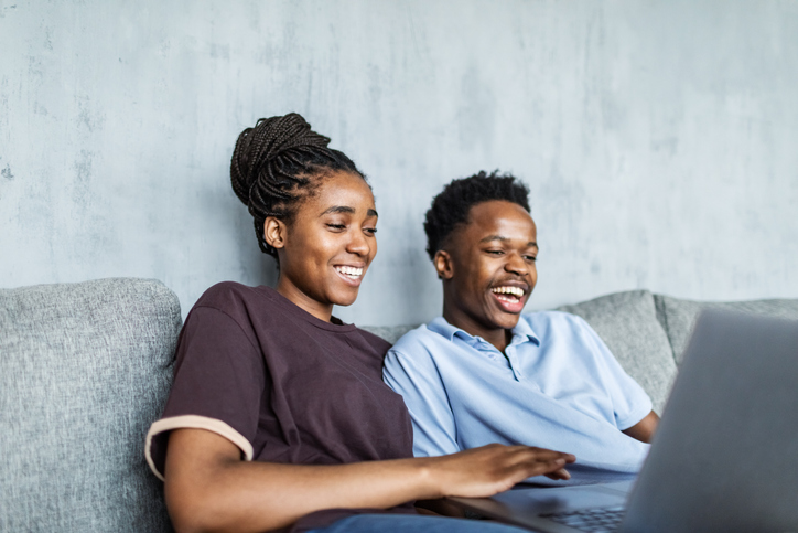 Young adult black couple watching comedy movie on laptop at home