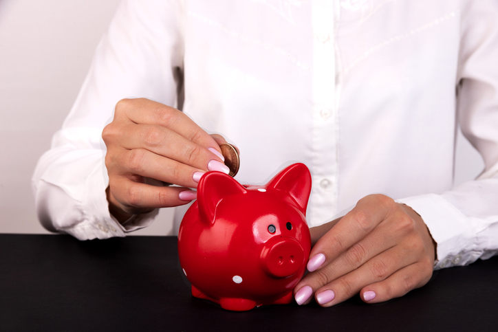 Woman Putting Coin In Piggy Bank, Indoors