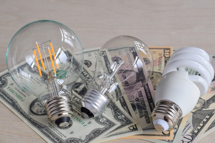 Three types of light bulbs on top of american dollars paper money