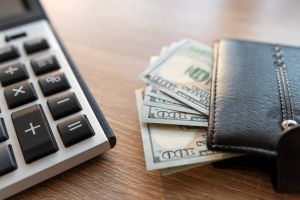 black male leather wallet and us dollar money with calculator