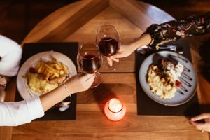 Two People Toasting with Glasses of Wine at a Restaurant Table