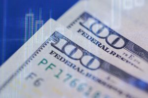 Close-up view of one hundred dollar bills with financial graph overlay