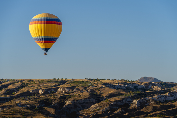 Yellow hot air balloon over the unique terrain of Cappadocia, Turkey